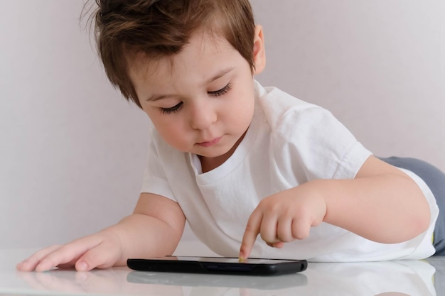 Asiatischer Junge spielt Handy. Kinderhände halten Smartphone und Tablet