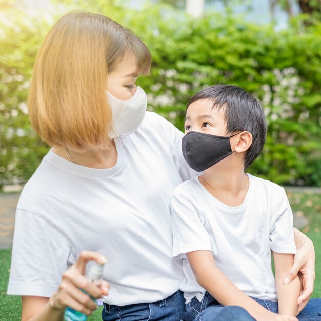 Asiatischer Junge trägt Gesichtsmaske und sieht ihn Mutter im Hausgarten aus. Konzentrieren Sie sich auf das Gesicht des Jungen.