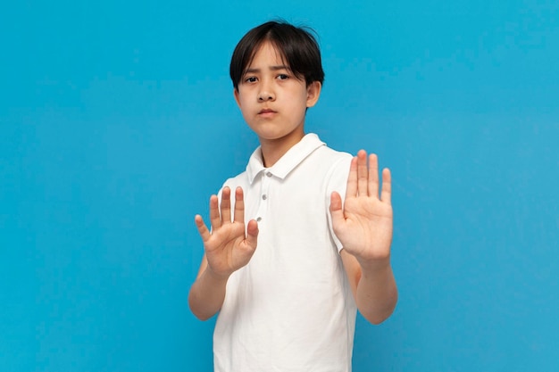 Foto asiatischer junge von zwölf jahren weigert sich und sagt nein auf blauem, isoliertem hintergrund, koreanisches kind