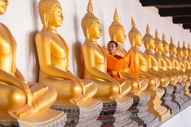 Asiatischer junger Anfängermönch bedeckt Stoffbuddha-Statue im Wat Phutthai Sawan Tempel, Ayutthaya, Thailand