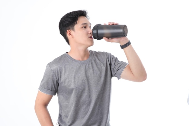 Asiatischer junger gutaussehender Mann in Sportkleidung und Molkenprotein-Shake-Flasche