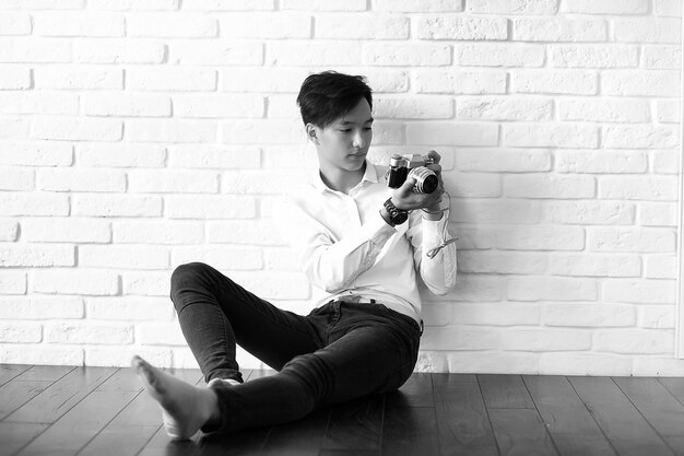 Asiatischer junger Mann benutzt eine Kamera im Studio