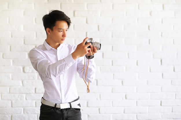 Asiatischer junger Mann benutzt eine Kamera im Studio