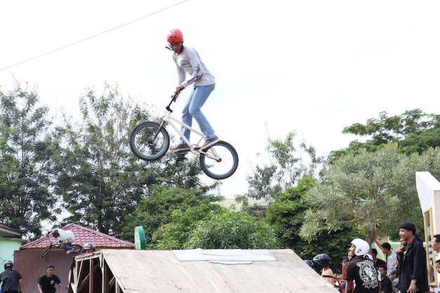 Asiatischer junger Mann demonstriert einige BMX-Freestyle-Tricks in der Luft.