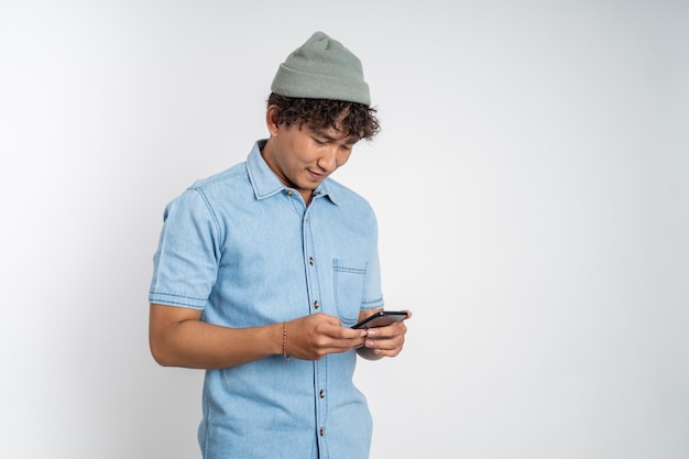 Asiatischer junger Mann, der auf den Bildschirm eines Mobiltelefons schaut