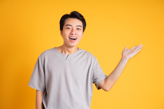 Asiatischer junger Mann, der auf einem gelben Hintergrund aufwirft