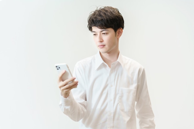 Asiatischer junger Mann, der benommen auf ein Smartphone starrt