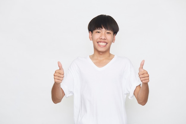 Asiatischer junger Mann, der ein T-Shirt trägt Daumen oben auf weißer Oberfläche trägt.