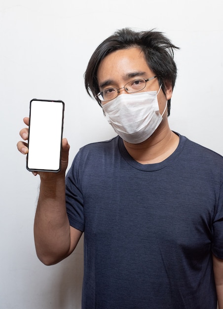 Asiatischer junger Mann, der Smartphone trägt Gesichtsmaske