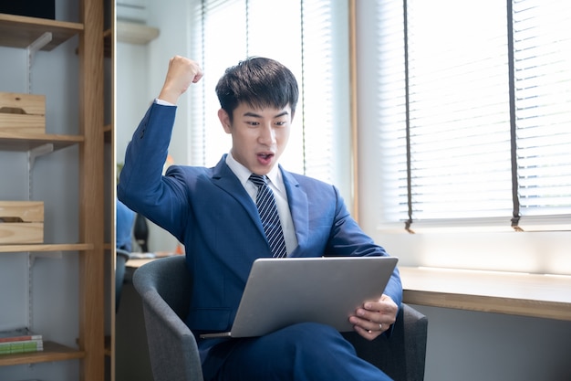 Asiatischer junger schöner Mann, der Laptop verwendet
