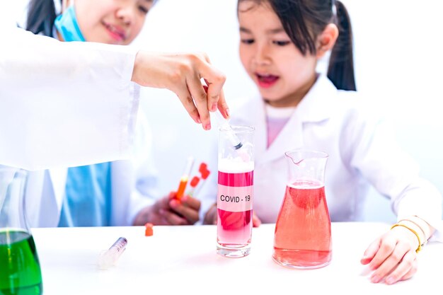 Asiatischer junger Wissenschaftler mit Röhrchenprobe COVID-19-Test. Kinderarzt experimentiert im Labor. Kindertraumberufskonzept.