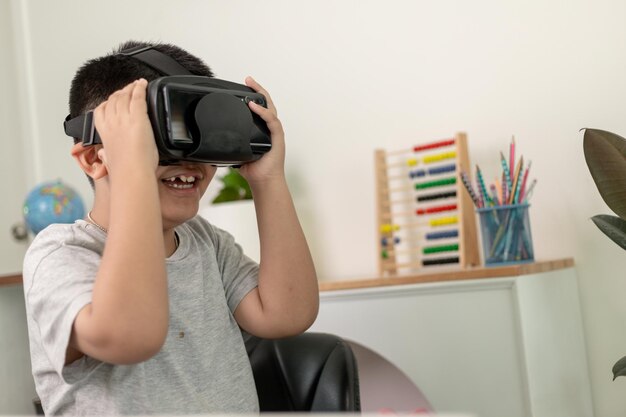 Asiatischer kleiner Junge mit VR-Brille, der zu Hause Wissenschaften studiert