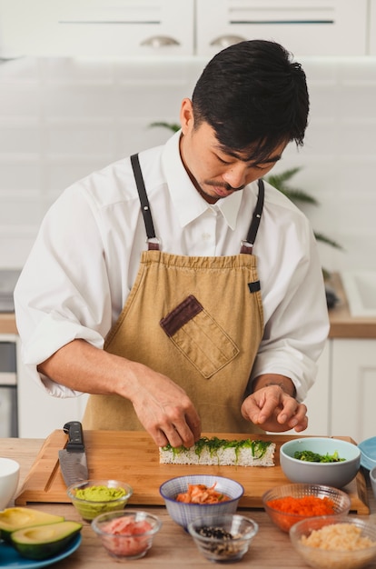 Asiatischer Koch fügt Zutaten zu Sushi-Rollen hinzu Online-Service für die Lieferung von Lebensmitteln japanische Küche rollt Soja