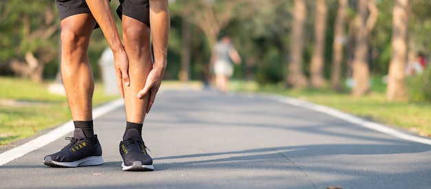 Asiatischer Läufer, der Wadenschmerzen und -problem hat, nach draußen laufen und trainieren