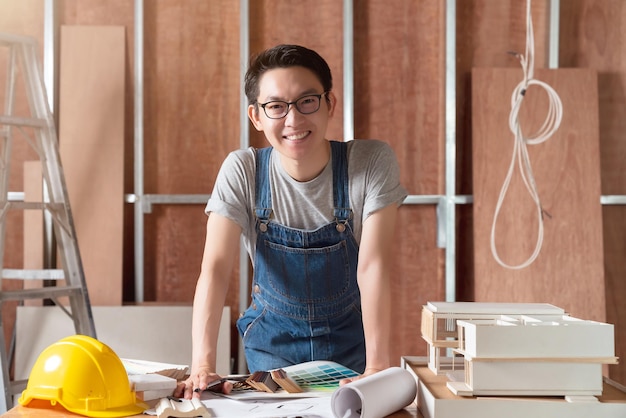 Asiatischer männlicher handwerker oder innenarchitekt mit intelligenter, attraktiver handlicher brille konzentriert sich auf die holzbearbeitung am standort