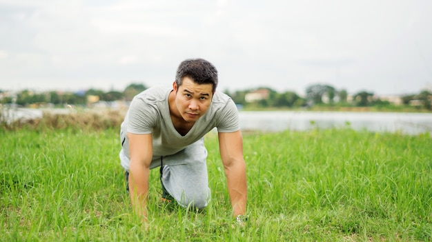 Asiatischer Mann bereitet sich für ein Training am allgemeinen Park, Weichzeichnung vor.