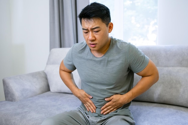 Asiatischer Mann berührt mit den Händen Bauchschmerzen durch Bauchschmerzen Medizin- und Gesundheitskonzept auf weißem Hintergrund