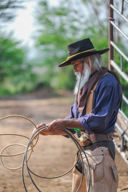 Asiatischer Mann-Cowboy fängt ein Kalb, um in einer Ranch gebrandmarkt zu werden