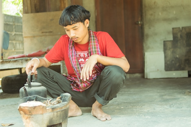 Asiatischer Mann, der auf alter Küche sitzt und kocht