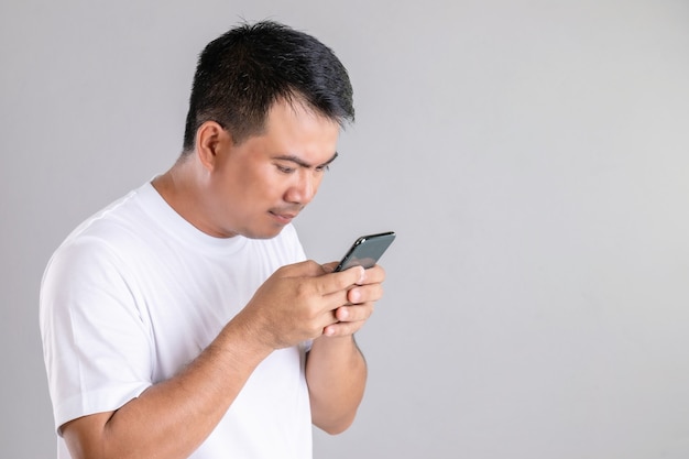 Asiatischer Mann, der auf Smartphone schreibt oder plaudert