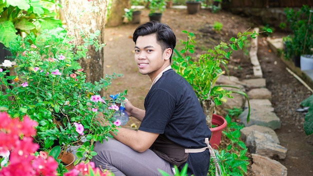 Asiatischer Mann, der Blume am Hausgarten pflegt