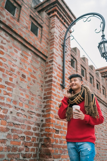 Asiatischer mann, der draußen am telefon spricht.