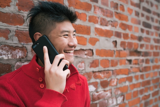 Asiatischer Mann, der draußen am Telefon spricht