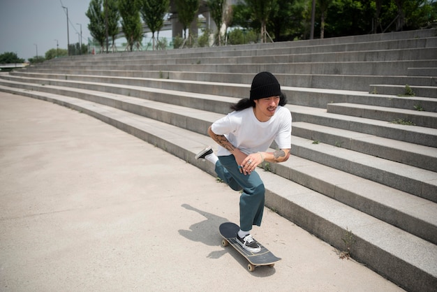 Asiatischer Mann, der draußen in der Stadt Skateboard fährt