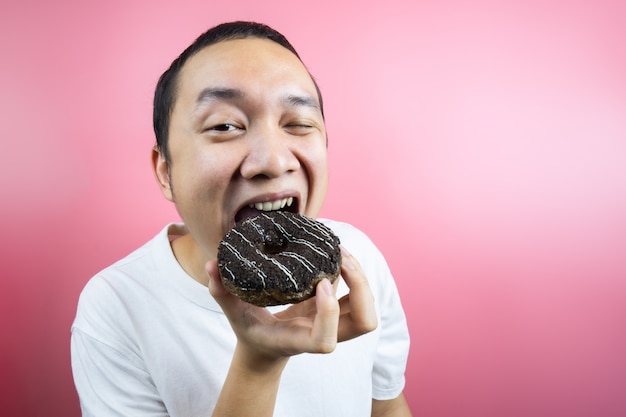 Asiatischer Mann, der einen köstlichen Donut isst