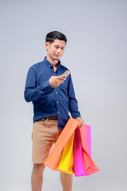 Foto asiatischer mann, der handy mit bunten papiertüten benutzt