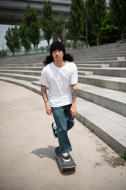 Asiatischer Mann, der in der Stadt Skateboard fährt