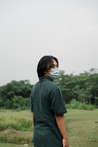 Asiatischer Mann, der in einem Park eine Maske trägt, um die Ausbreitung von Covid 19 zu verhindern