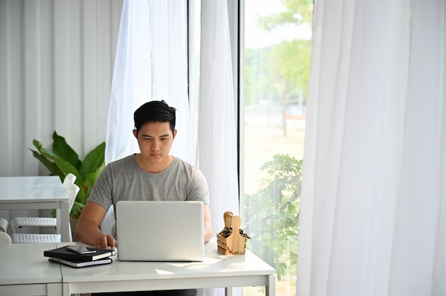 Asiatischer Mann, der Laptop-Computer am Café verwendet.