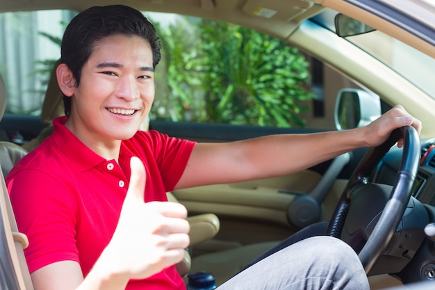 Asiatischer Mann, der neues Auto fährt