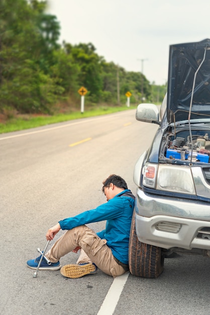 Asiatischer Mann, der Probleme mit seinem defekten Auto hat