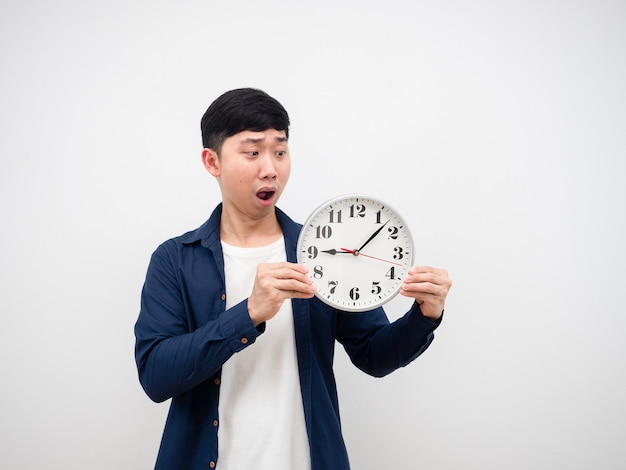 Asiatischer Mann, der sich schockiert fühlt, wenn er auf die Uhr in seiner Hand schaut, spätes Konzept auf weißem Hintergrund