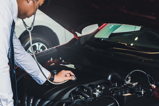 Asiatischer Mann, der Stethoskopautoinspektion Gummireifenauto hält Schließen Sie herauf Hand