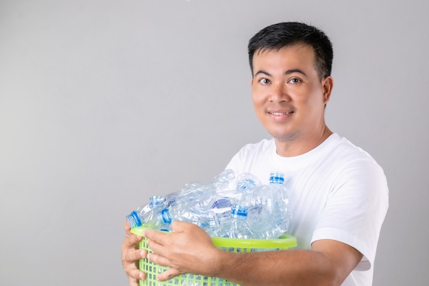 Asiatischer Mann, der viele leere klare Wasserflaschen hält