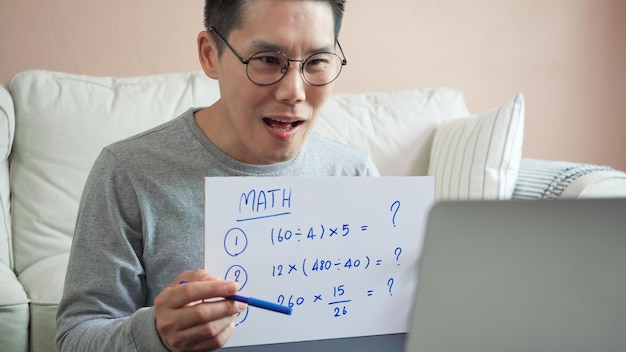 Foto asiatischer mann, der zu hause mathe-e-learning unterrichtet