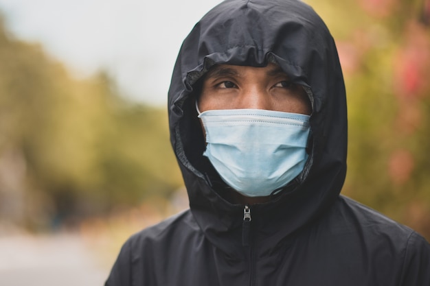 Asiatischer Mann ein tragendes Gesichtsmaskenkonzept neue normale soziale Distanzierung