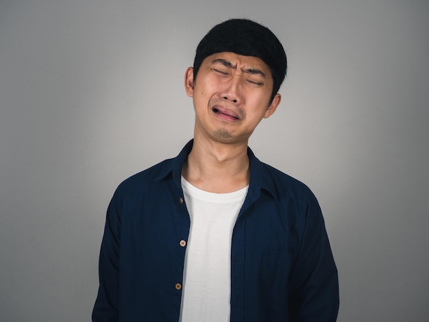 Asiatischer Mann fühlt sich deprimiert und weint über ein unglückliches Leben isoliert