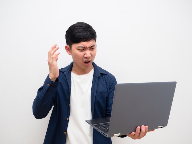 Asiatischer Mann fühlt sich schockiert und traurig mit Laptop in der Hand auf weißem, isoliertem Hintergrund