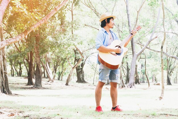 Asiatischer Mann Gitarre spielen im Park