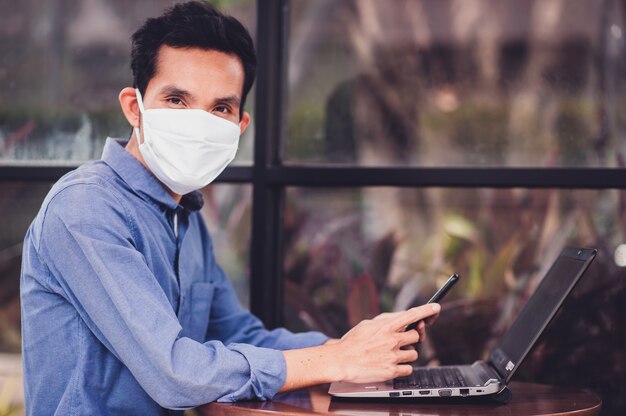 Asiatischer Mann in der Gesichtsmaskenarbeit im Bürokonzept, das neue normale soziale Distanzierung arbeitet