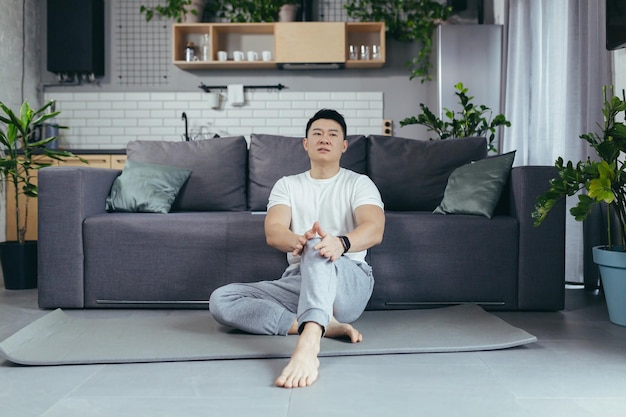 Asiatischer Mann in Sportbekleidung, der zu Hause unter Knieschmerzen leidet
