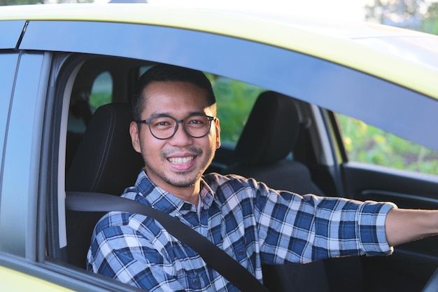 Asiatischer Mann lächelt in die Kamera, während er sein Auto fährt