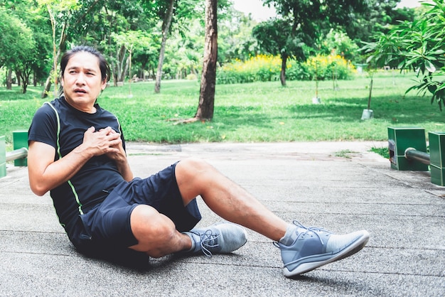 Asiatischer Mann leidet an Brustschmerzen Aufgrund wiederkehrender Herzerkrankungen beim Training im Park