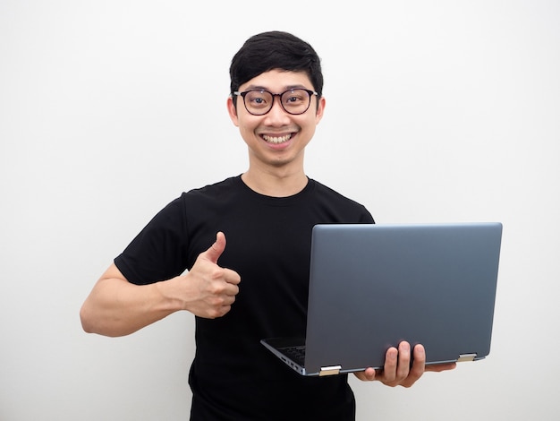 Asiatischer Mann mit Brille hält Laptop-Daumen hoch und glückliches Lächelngesicht auf weißem Hintergrund