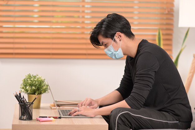 Asiatischer Mann mit Computertablette im Wohnzimmer.