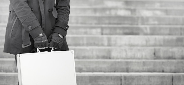 Asiatischer Mann mit einem Metallkoffer in der Stadt. Asiatisches und silbernes Gehäuse. Asiate mit einem Koffer für Killer. Detektiv mit der Ware im Koffer.